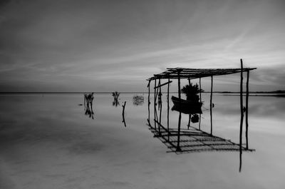 Silhouette people sitting by sea against sky