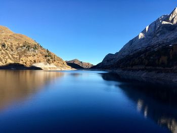 Scenic view of lake and mountains against clear blue sky