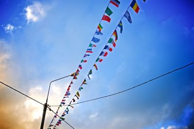 Low angle view of multi colored flags hanging against blue sky