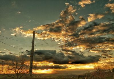 Scenic view of field against cloudy sky at sunset