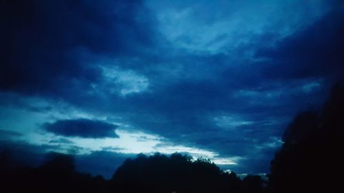 Silhouette of trees against cloudy sky