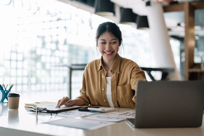 Smiling businesswoman using laptop at office