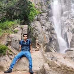 Full length of young man sitting on rock