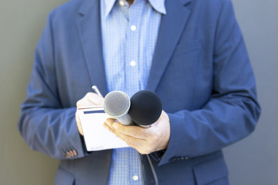 Midsection of man holding microphone
