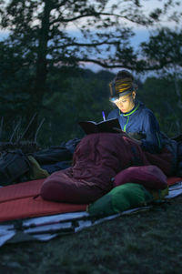 Woman writing in book while sitting on field