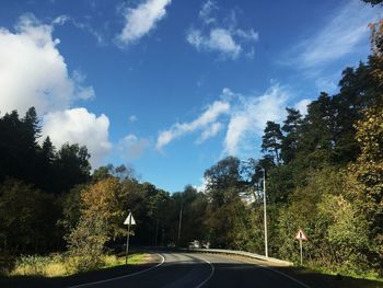 Road by trees against sky