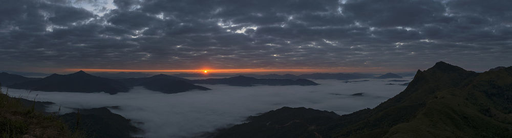 Scenic view of landscape against dramatic sky at sunset