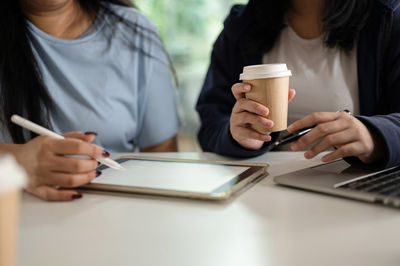 Midsection of woman using mobile phone at table