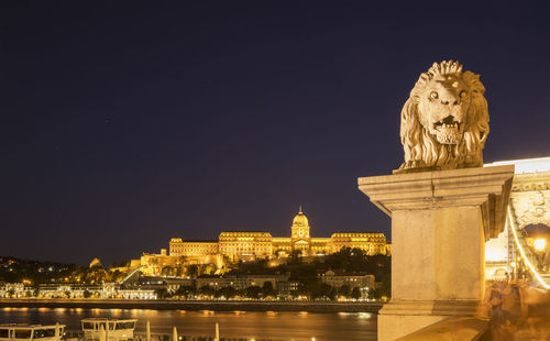 Statue on budapest waterfront against clear sky at night