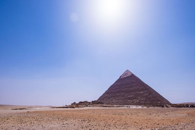 Pyramid at desert against clear sky on sunny day