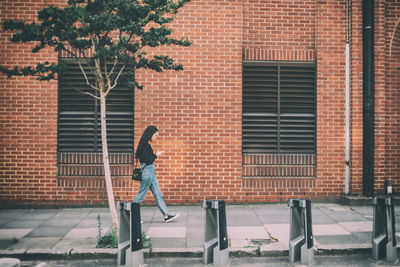 Full length side view of woman against building