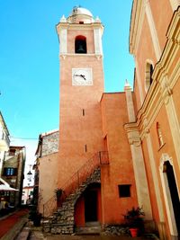 Low angle view of clock tower amidst buildings against clear sky