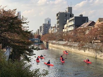 People kayaking in river by buildings