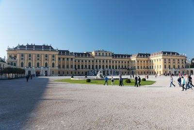 Group of people in front of buildings against clear blue sky