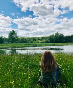 Rear view of woman looking at lake against sky