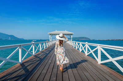 Rear view of woman by sea against clear blue sky