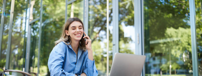 Portrait of young woman using laptop while sitting at park