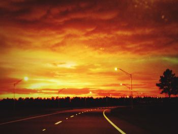 Scenic view of road against cloudy sky at sunset