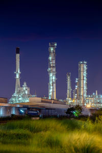 Illuminated factory against sky at night