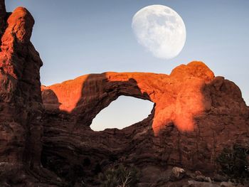 Low angle view of natural arch against moon