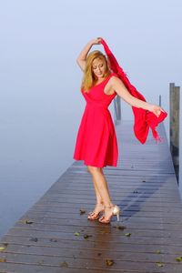 Full length of woman standing on pier at lake during foggy weather