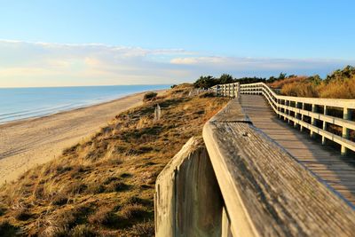 Footpath at beach against blue sky during sunset