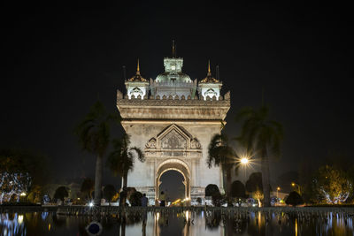 Illuminated building in city against clear sky at night