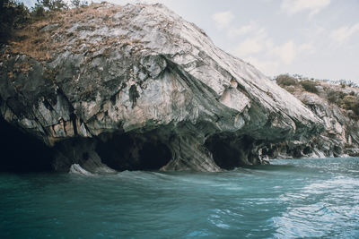 Rock formation in sea against sky