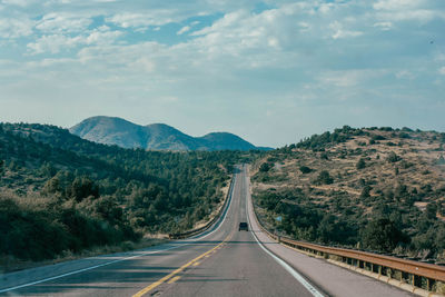 Road leading towards mountains against sky