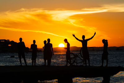 dozens of young people, in silhouette, are seen on top of the crush bridge having fun. 