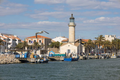 Buildings by sea against sky