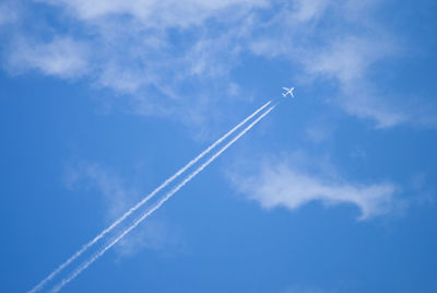 Low angle view of vapor trail against blue sky