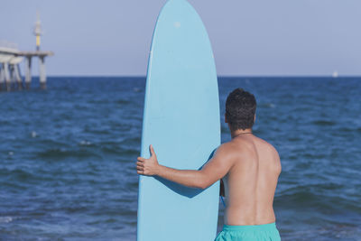 Shirtless man with surfboard at beach