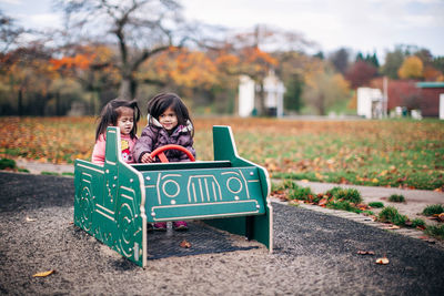 Siblings playing with toy car on roadside