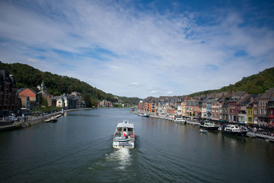 Boats in river amidst buildings in city against sky