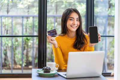 Young woman using phone on table