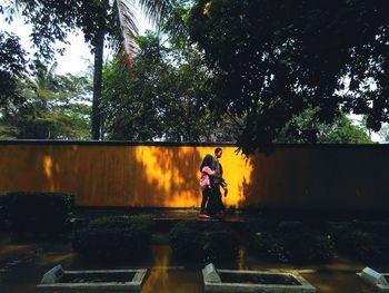 Woman standing by trees against sky