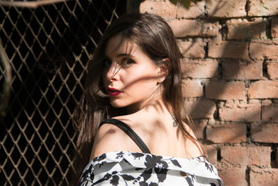 Portrait of woman against brick wall