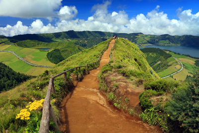 Road amidst green landscape against sky