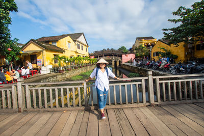 Portrait of woman standing on bridge against sky