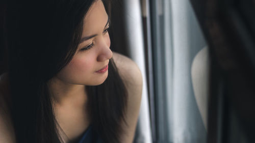 Portrait of young woman looking through window