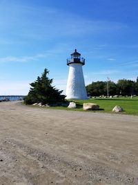 Lighthouse amidst trees and buildings against sky