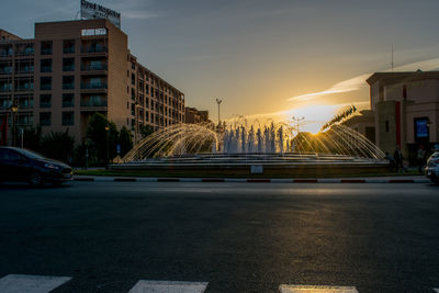 Road in city against sky during sunset