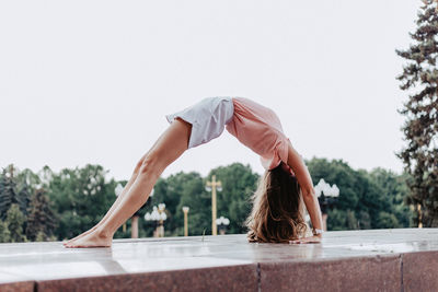 Midsection of woman with arms raised against sky