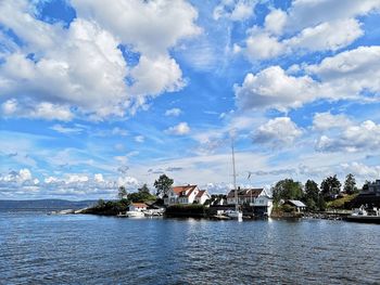 Scenic view of river by buildings against sky