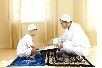 Father and son reading quran at home