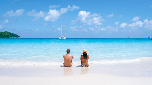 Rear view of woman standing at beach against sky