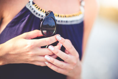 Midsection of woman holding sunglasses