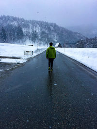 Rear view of man walking on road during winter