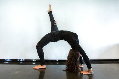 Side view of woman exercising against wall